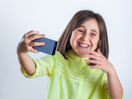 Pretty teenage girl with mobile phone in studio. Selfie.の写真素材