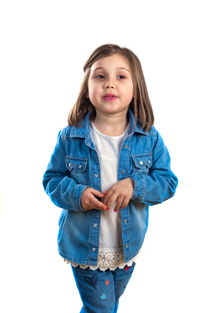 little girl in jeans posing for the camera in the studio.の写真素材