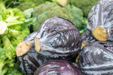 Purple cabbages and broccoli stacked at a farmers' market.