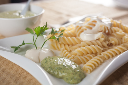 Pasta in white plate, parsley, bowl with mayonnaise sauce.の写真素材
