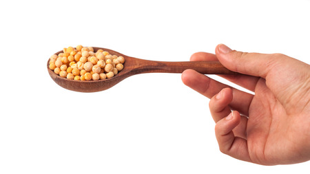 spoon in hand with yellow peas on white background.の写真素材