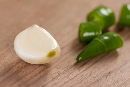sliced green peppers and garlic on a wooden board.の写真素材