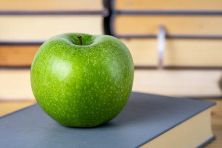 books and green apple on the wooden tableの写真素材