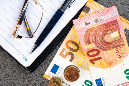 Money euro, notebook and pen on stone backgroundの写真素材