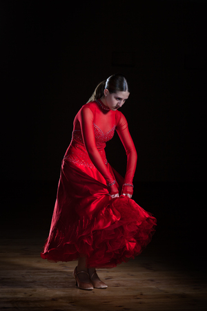 Beautiful young hispanic flamenco dancer in red dress isolated on black backgroundの写真素材