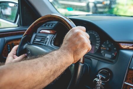 Male driver hands holding steering wheel. Man driving a car. Transportation.の写真素材