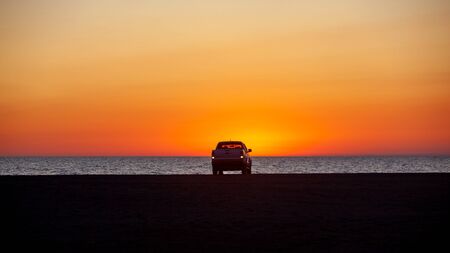 Pick-up truck parked in front of Black Sea at beautiful sunset. Nature.の写真素材