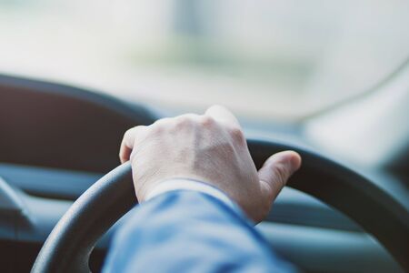 Men's hands on the wheel of the car, transportation