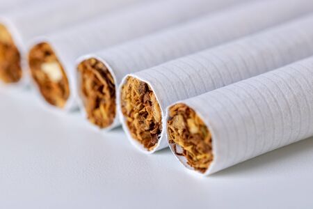 Closeup of a pile of cigarettes over white background. Danger.