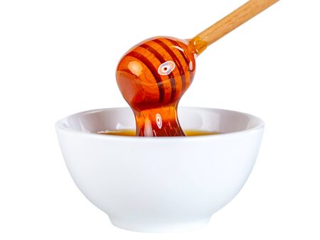 honey dripping from woodin dipper to ceramic bowl, foodの写真素材