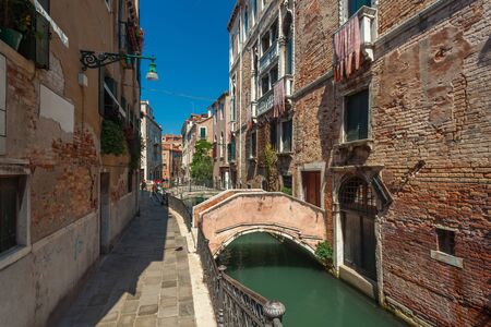 View of narrow Canal with boats and gondolas in Venice, Italy. Venice is a popular tourist destination of Europeの写真素材