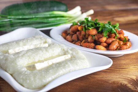 Lobio is a Georgian dish, ghomi and green onion in a plate on wooden table, food