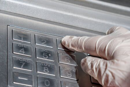 Woman's hand in gloves inserting pin code, ATM. Financeの写真素材