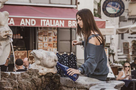 Amalfi, Italy - 1 November, 2019: A girl fills her water bottle at a fountain in Amalfi, Italyのeditorial素材