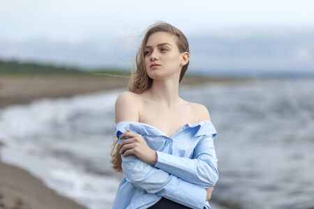 Beautiful young blonde girl in a blue shirt relaxing on the sea, resortの写真素材