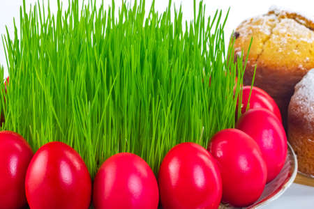Red Easter eggs around wheat grass on the plate isolated on white background, Easter cake