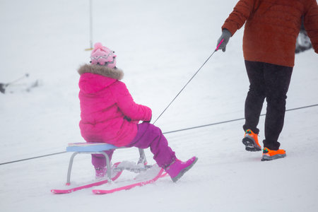 Kids with sledge climbing at the snowy hill on winter park in Bakuriani, Georgiaの写真素材