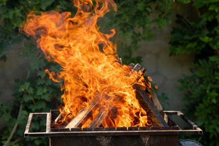 Wood burns in a metal grate to produce charcoal for the grill. barbecue