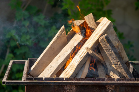 Wood burns in a metal grate to produce charcoal for the grill. barbecueの写真素材