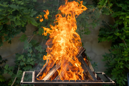Wood burns in a metal grate to produce charcoal for the grill. barbecueの写真素材