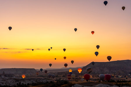Hot air balloon flying over rocky landscape at sunrise in Cappadocia. Travelの写真素材