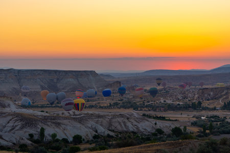 Hot air balloon flying over rocky landscape at sunrise in Cappadocia. Travelの写真素材
