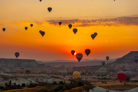 Hot air balloon flying over rocky landscape at sunrise in Cappadocia. Travelの写真素材
