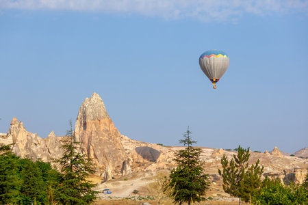 Hot air balloon flying over rocky landscape at sunrise in Cappadocia. Travelの写真素材