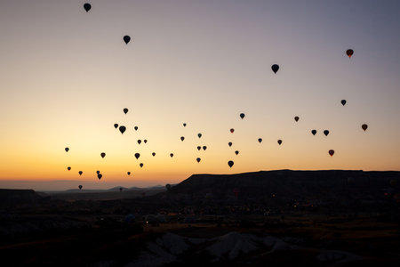 Hot air balloons flying over rocky landscape at sunrise in Cappadocia.の ...