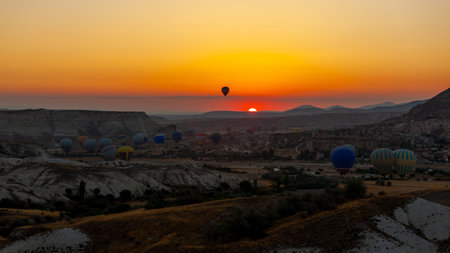 Hot air balloon flying over rocky landscape at sunrise in Cappadocia. Travelの写真素材