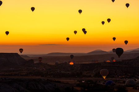 Hot air balloon flying over rocky landscape at sunrise in Cappadocia. Travelの写真素材
