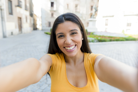 attractive latin woman in her twenties happy talking on her smart phone on holidays in europe.の写真素材