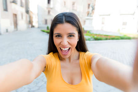 attractive latin woman in her twenties happy talking on her smart phone on holidays in europe.の写真素材