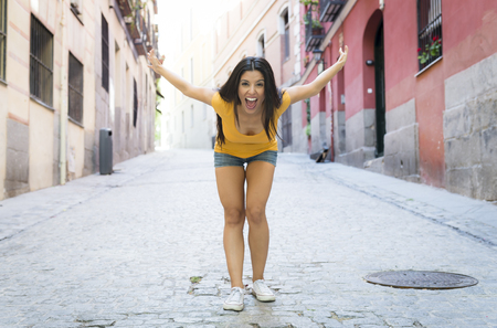 young attractive latin woman happy and excited posing on modern urban European city background in tourism and holiday travel concept の写真素材