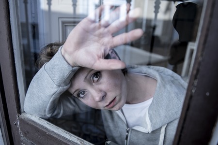 young beautiful depressed unhappy caucasian woman looking worried and sad through the window at home. feeling worthless and in pain. closeup. Depression and crisis conceptの写真素材