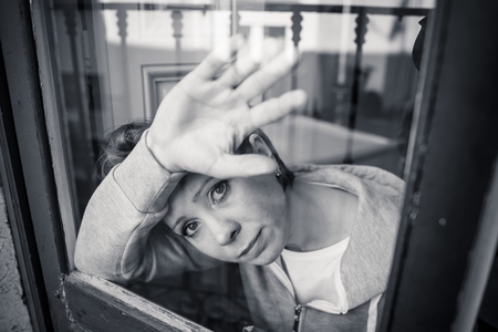 young beautiful depressed unhappy caucasian woman looking worried and sad through the window at home. feeling worthless and in pain. closeup. Depression and crisis conceptの写真素材