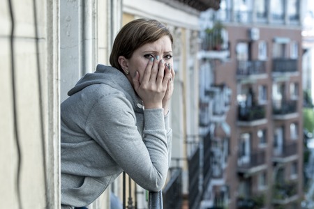 Young attractive,red haired, unhappy lonely caucasian woman with depression looking sad on the balcony at home. feeling desperate and hopeless in depression and mental health female conceptの写真素材
