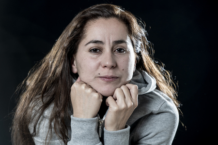 close up of young beautiful latin woman, scared and nervous on a black background in a negative emotional online bullying concept.の写真素材