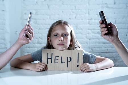 mother and father using mobile phone neglecting little sad ignored daughter bored and lonely feeling abandoned and disappointed in parents mobile cell smart phone addiction bad behavior conceptの写真素材