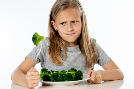 Nutrition & healthy eating habits for kids healthy eating concept. Children do not like to eat vegetables. Little cute kid girl refuse to eat healthy broccoli vegetables on a white backgroundの写真素材