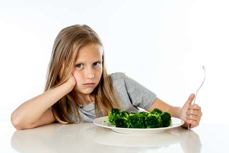 Nutrition & healthy eating habits for kids healthy eating concept. Children do not like to eat vegetables. Little cute kid girl refuse to eat healthy broccoli vegetables on a white backgroundの写真素材