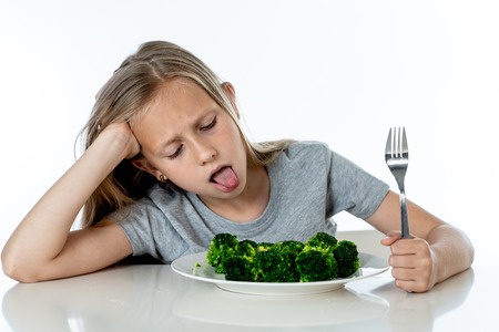Nutrition & healthy eating habits for kids healthy eating concept. Children do not like to eat vegetables. Little cute kid girl refuse to eat healthy broccoli vegetables on a white backgroundの写真素材