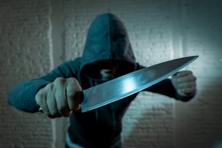 close up of a hands holding a knife of dangerous hooded man standing in the dark in London knife...