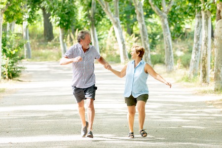 Happy beautiful senior couple in love walking and holding hands in the park enjoying life outdoors. Happy and active retirement conceptの写真素材