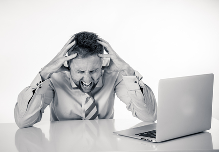 Business, people, deadline and technology concept - stressed entrepreneur businessman with laptop computer at office feeling angry and desperate.の写真素材