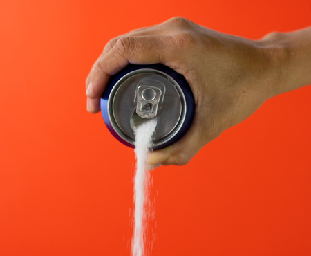 Hand holding soda can pouring lots of sugar in metaphor of sugar content of a refresh drink in unhealthy nutrition, diet, sweet and carbonated drinks addiction and unhealthy food concept.の写真素材