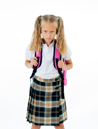 Sweet beautiful little girl in school uniform feeling angry and frustrated looking at the camera isolated on white background in homework learning difficulties back to school and education concept.の写真素材
