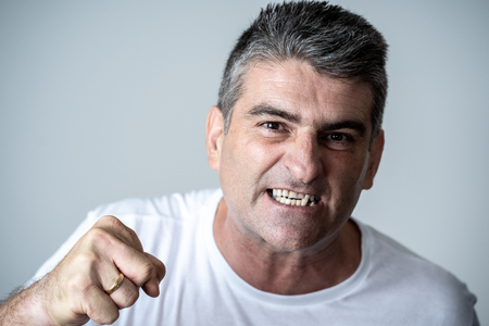 Portrait of a mature 40s to 50s white angry and upset man looking furious and aggressive human emotions facial expressions and feelings concept isolated on grey background.の写真素材