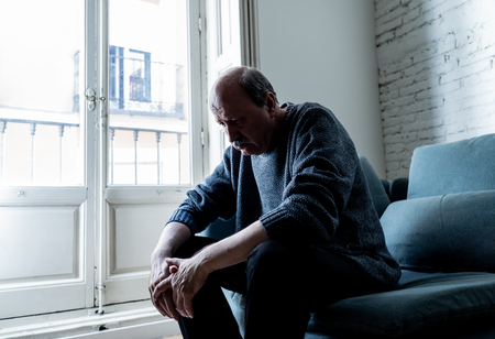 Overwhelmed old senior man suffering alone at home feeling confused sad alone on couch at home in Aging Retirement widower Dementia and Alzheimer concept.の写真素材