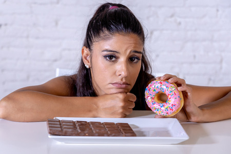 Hungry beautiful young woman unhappy craving sweet chocolate and doughnuts and cannot eat in Dieting Weight loss Sugar addiction Diabetic and unhealthy healthy food concept.の写真素材